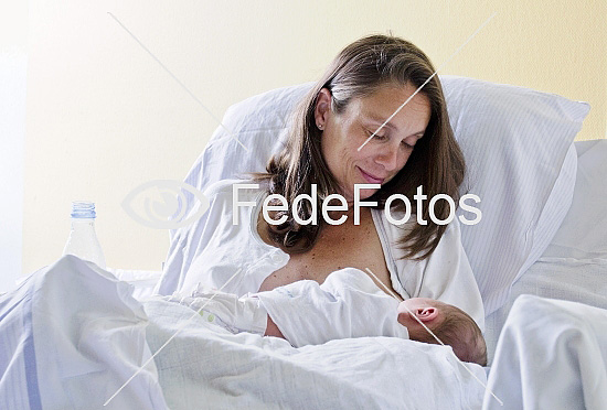 Træt kvinde ammer nyfødt baby